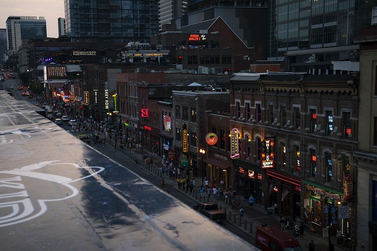 Lower Broadway at dusk, neon signs lit along the honky-tonks